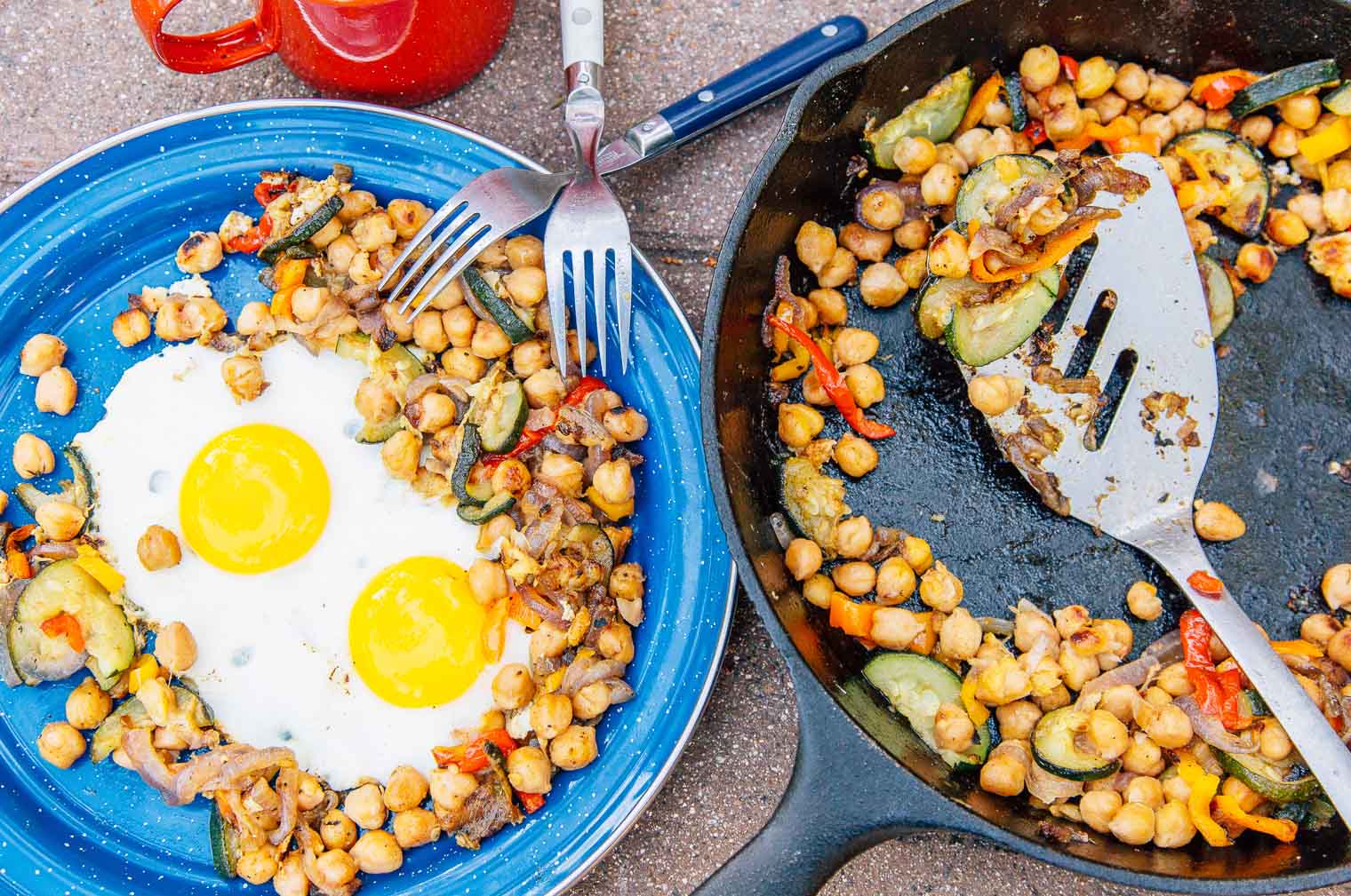 Cast iron skillet with chickpeas next to a blue camping plate with fried eggs