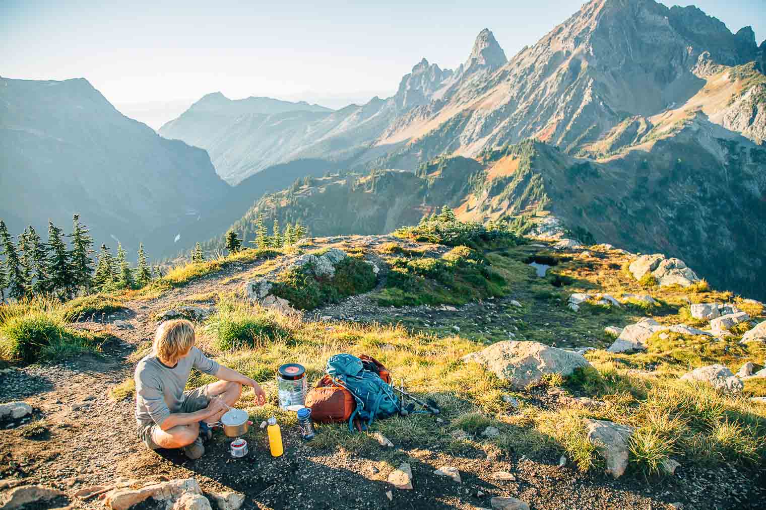 Michael cooking over a backpacking stove with mountains in the background