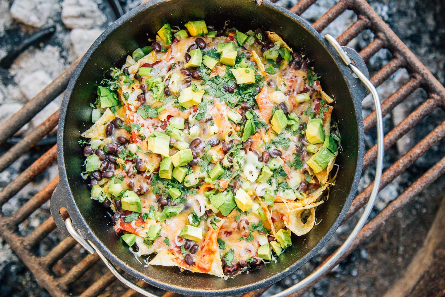 Overhead view of nachos in a Dutch Oven over a campfire