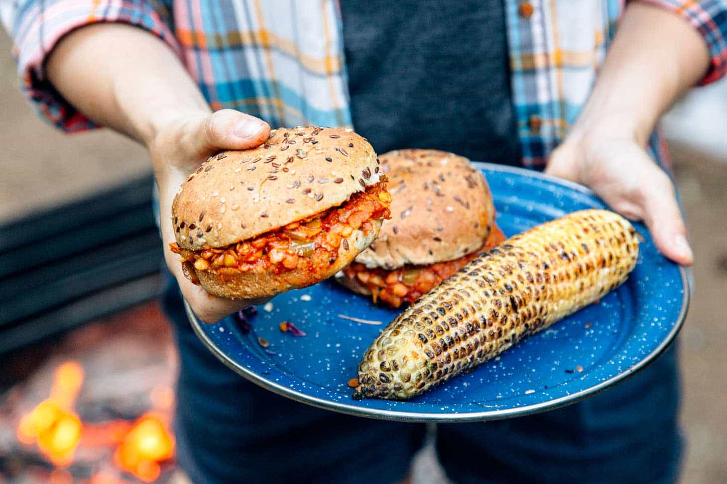 Red lentil sloppy joes on a blue camping plate with grilled corn.