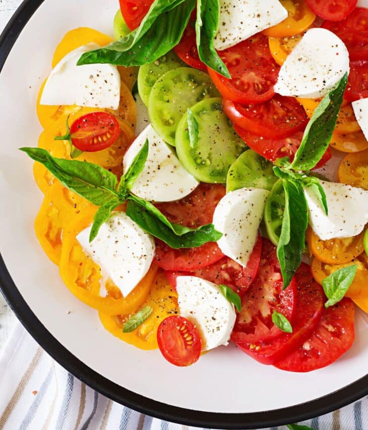 Tomatoes basil and cheese on a plate.