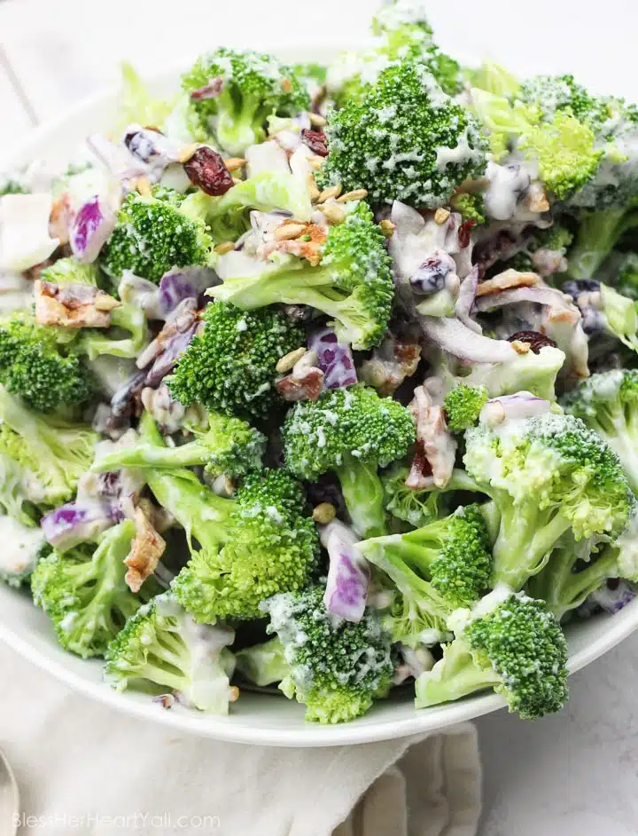 A colorful broccoli salad features chunks of red cabbage, specks of pecans and cranberries, all glazed in a creamy dressing.